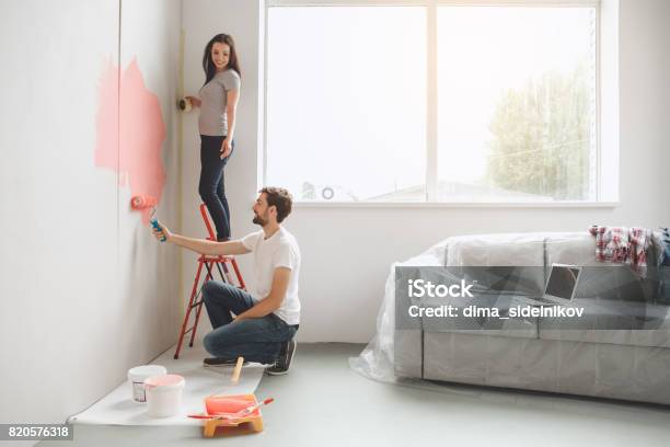 Joven Pareja Haciendo Apartamento A Repararse Foto de stock y más banco de imágenes de Pintar - Pintar, Casa, Pared