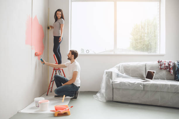 giovane coppia che fa riparazione appartamento insieme - uomo dipinge foto e immagini stock