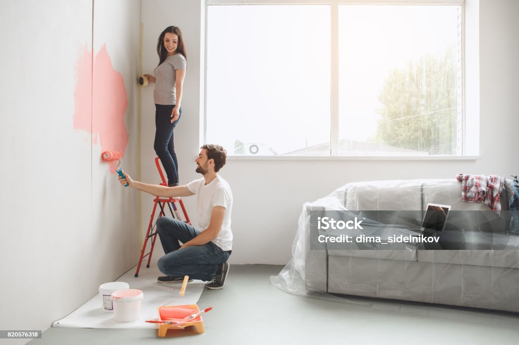 Young couple doing apartment repair together themselves Young man and woman doing apartment repair together paint walls Painting - Activity Stock Photo