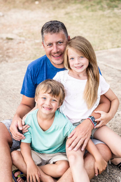 istock Father, son and daughter cuddling on the beach 820582832