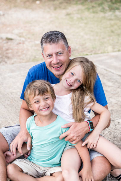 istock Father, son and daughter cuddling on the beach 820583134