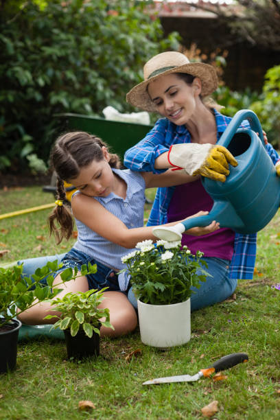 istock Daughter assisting mother in watering potted plants 820583348