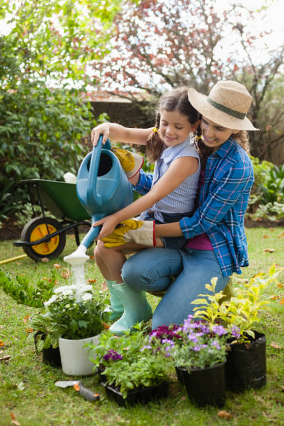 istock Happy mother teaching daughter to water plants 820583576