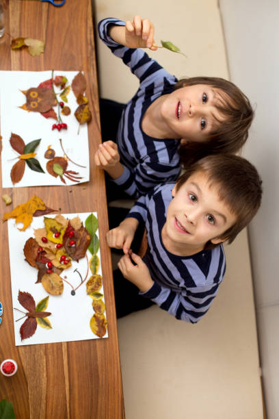 istock Sweet children, boys, applying leaves using glue while doing art 820584844