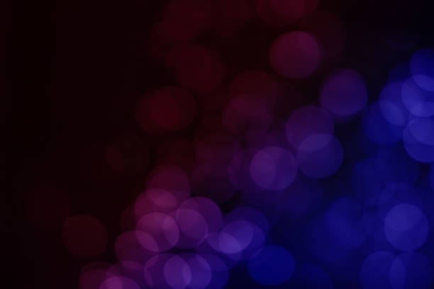 Bokeh of sprayed water in the air on black background is colorful with pink, purple and blue. The picture looks like a lot of transparent balloons floating in the sky at night.