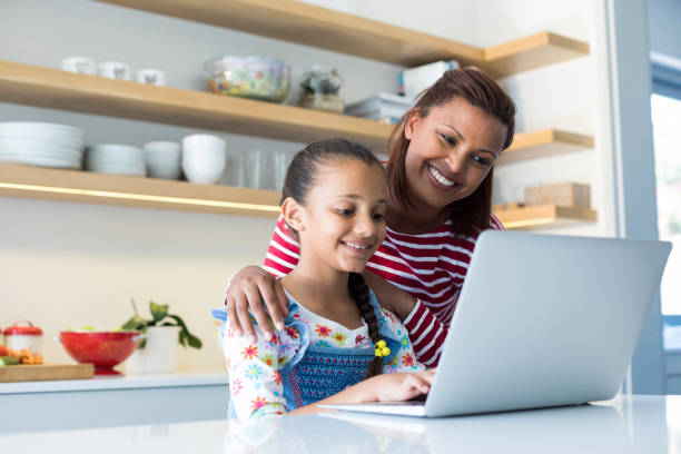 istock Mother and daughter using laptop in kitchen worktop 820592446