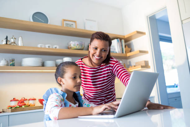 istock Mother and daughter using laptop in kitchen worktop 820592494