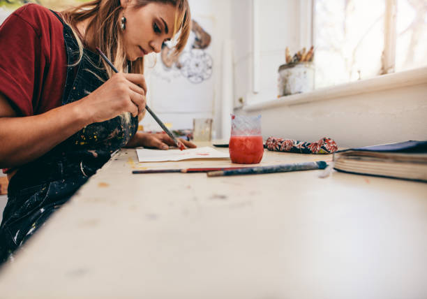 Image of beautiful woman drawing pictures in her workshop. Female artist painting in her studio.