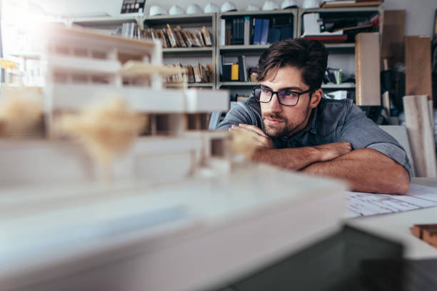 istock Architect in office looking at house model 820599964