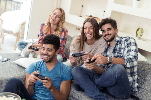 Positive friends sitting on the couch  play video game and smiling.