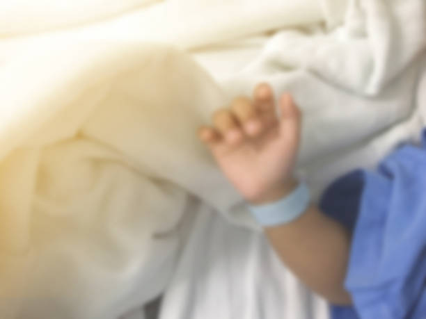 Blurry background of illness hand kid with name tag bracelets on bed in hospital Blurry background of illness hand kid with name tag bracelets on bed in hospital baby bracelet stock pictures, royalty-free photos & images