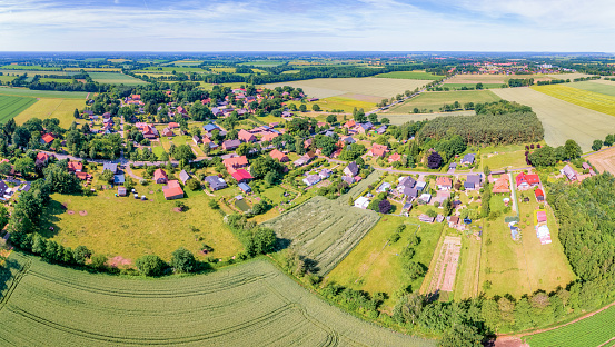 Aerial view of a small village and agricultural land in Germany / Lower Saxony. Splietau is a district of the town of Dannenberg (Elbe) in the municipality of Elbtalaue in the district of Lüchow-Dannenberg in Lower Saxony. The village is near east of Dannenberg. It is located on the Lüchower Niederterrasse. In 2004 the village had 205 inhabitants. Before the settlement was nearly completely destroyed by a fire in the spring of 1870, Splietau was a closely cultivated village. In addition, the old oak trees are also a part of the town. South of the town is a dike, which had served as a backwater protection before the Jeetzelderderderung water and dichbaulich was redesigned in the middle of the 20th century. Thus, in 1888, a flood of lowland areas in Lüchow-Dannenberg and the entire village of Splietau had taken place.