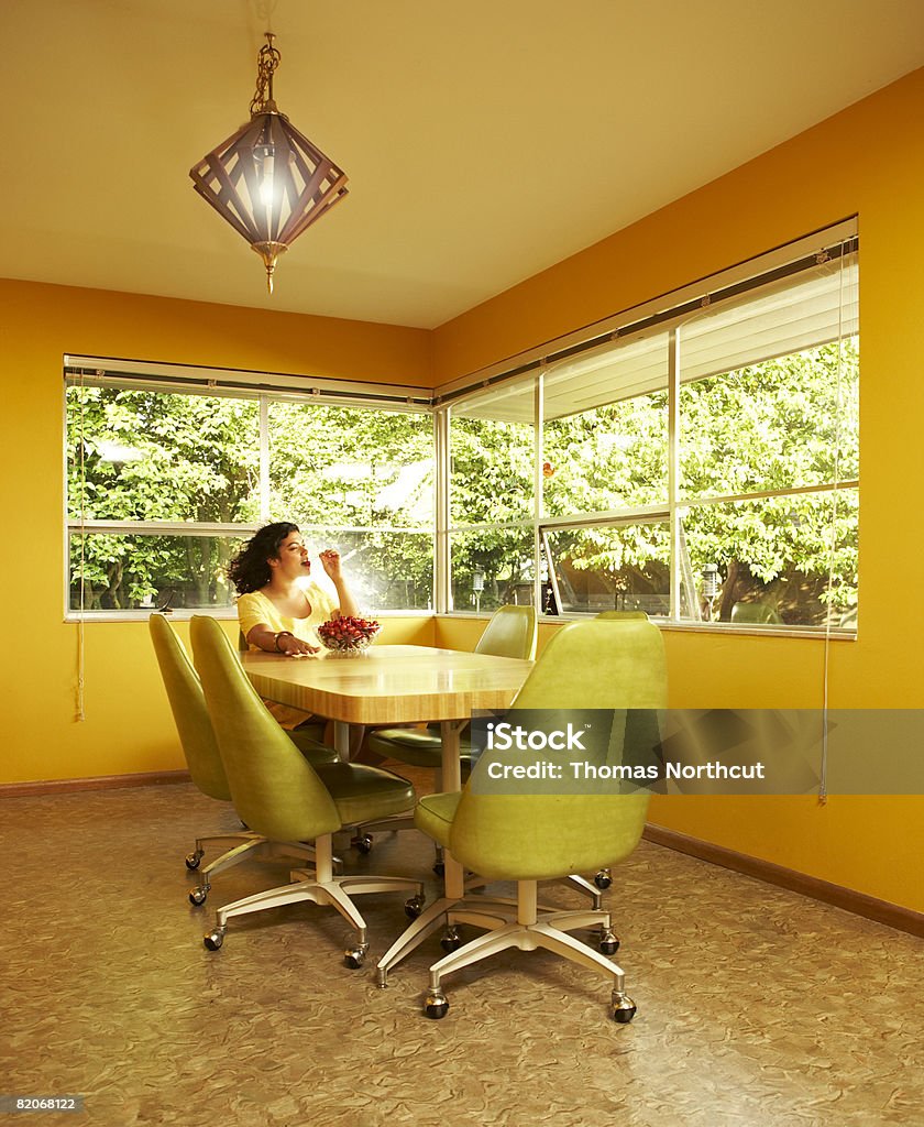 Woman eating cherries in dining room  Yellow Stock Photo