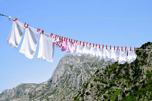 istock White laundry, hitched
 with red clothespins, fluttering in the wind 820694358