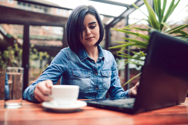 istock Young Woman Freelancer Working with Laptop Computer And Drinking Coffee in a City Cafe 820724454