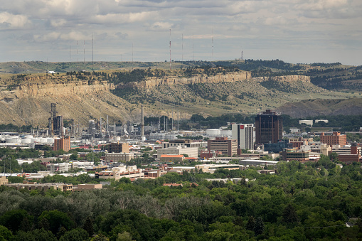 Looking from a ridge, clouds roll over downtown Billings, Montana with its office buildings, hotels, and petroleum refinery towers and smoke stacks.