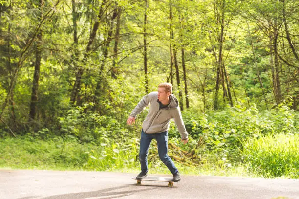 Red-haired male skateboards through forest and tries some tricks out