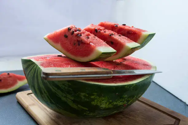 Half watermelon with three slices on the top and knife