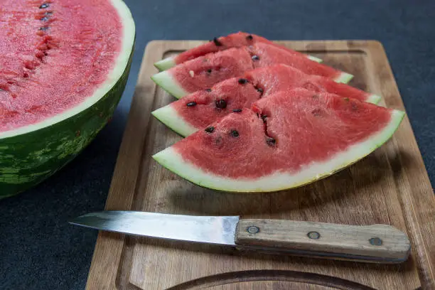 Freshly cut watermelon slices on the wooden board woth knife