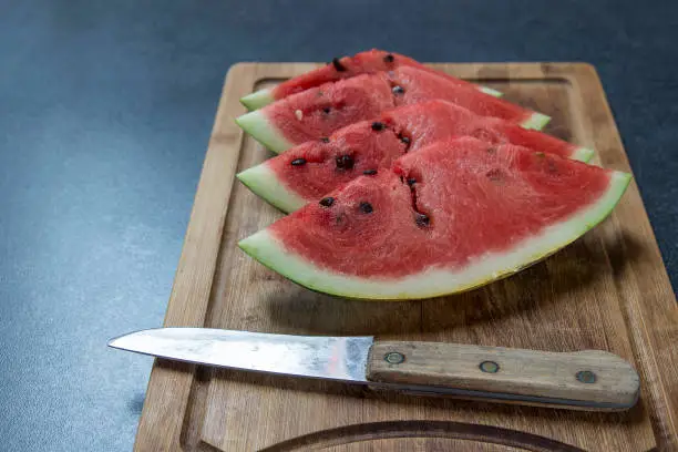 Watermelon slices laying on the wooden board with knife