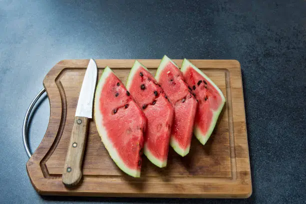 Four watermelon slices on the wood with knife