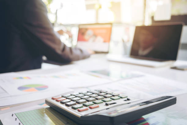 istock businessman using laptop and calculator at office desk and many document data graph in morning light, business concept. 820741152