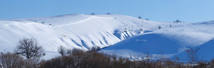 Panoramic view of snow-covered hills in central Russia. Winter sunny day.