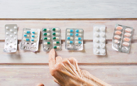 Senior woman hands picking her today medical pills