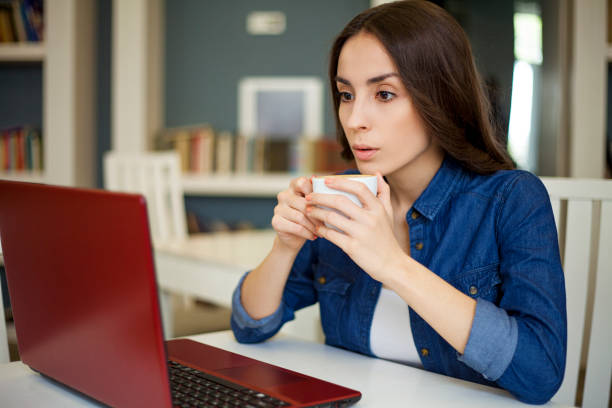 istock young brunette woman drinks coffee while watching a movie on laptop and relaxing in library cafe 820761114