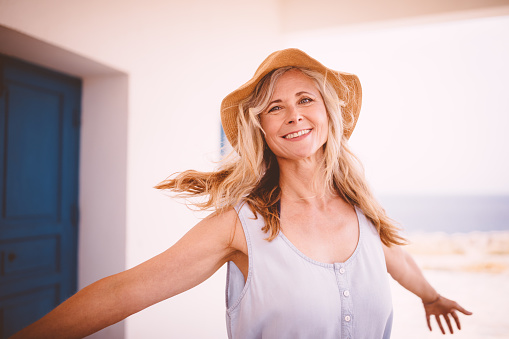 Happy senior woman with beach hat having fun while on island summer holidays in Italy