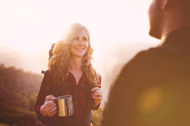 istock Senior woman hiker resting with drink standing on mountain edge 820764716
