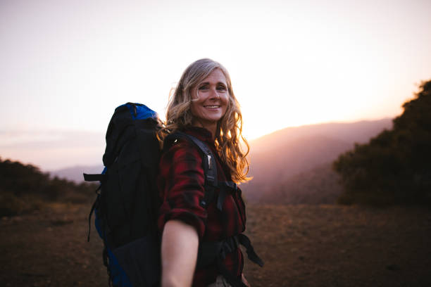 istock Happy senior woman with backpack hiking on mountains at sunset 820765646