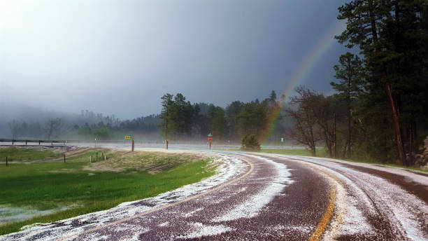 Rainbow After Intense Hail Storm on a South Dakota Highway near Keystone. A magnificent scene of a rainbow after a hailstorm (hailbow) on Highway 40 near Keystone, South Dakota.  This picture was taken right after driving through 8 inches of quarter sized hail a few miles away on 5/20/16. keystone south dakota photos stock pictures, royalty-free photos & images
