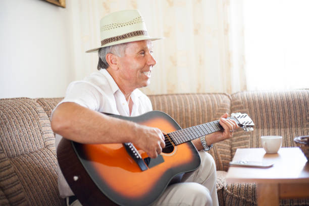 istock Senior man at home play guitar 820773118