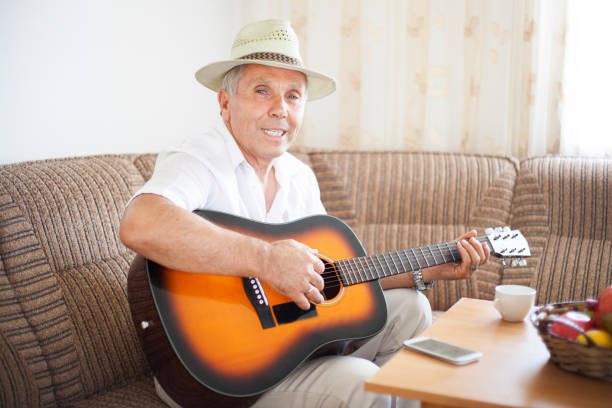 istock Senior man at home play guitar 820773400