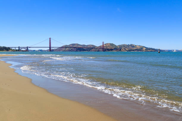 A photograph taken on an empty beach at Crissy Field, with the Golden Gate Bridge in the distance.