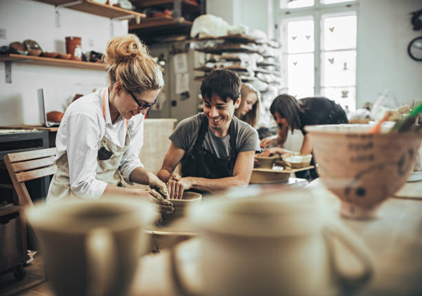 istock Man and woman in workshop working on pottery wheel 820783338