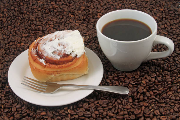 Coffee cup with pastry on a coffee bean background