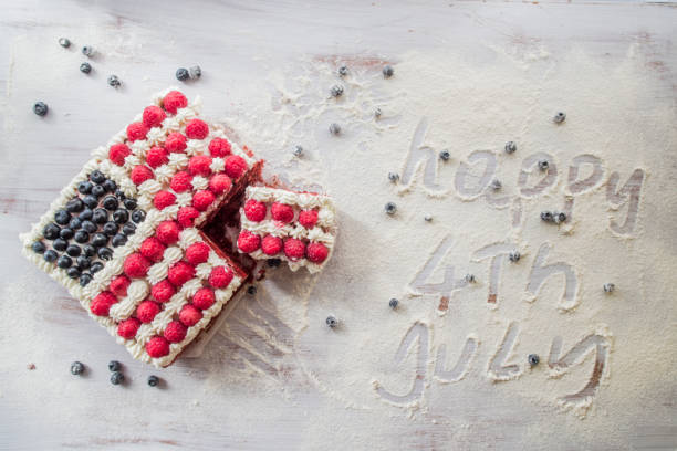 American flag is reproduced in a a cake with raspberry ,whipped cream and blueberry, over a white background, \