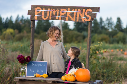 Mom and daughter stand behind a makeshift table with a sign that says 