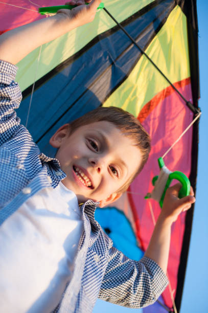 istock happy little boy holding kite over his head and looking into the camera 820807498
