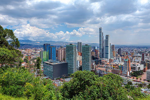 Bogota, Colombia - High angle view of the downtown district in the Andean capital city of Bogota, Colombia in South America. The tall concrete towers to the right are the Bacatá Towers the tallest building in the Country. It is still under construction. The red terracotta roof tiled buildings to the left of the image is La Candelaria, where the city was founded in 1538. It is the oldest part of the city. Located at about 8500 feet above mean sea level, with a population of almost 10 Million, Bogota is one of the largest cities in Latin America. Photo shot in the morning sunlight; horizontal format. The location from where the image was shot makes it an uncommon image: not many photographers will stop at the location with an expensive DSLR. The area is considered as high risk for mugging and even stabbing. Camera: Canon EOS 5D MII. Lens: Canon EF 24-70 F2.8L USM.