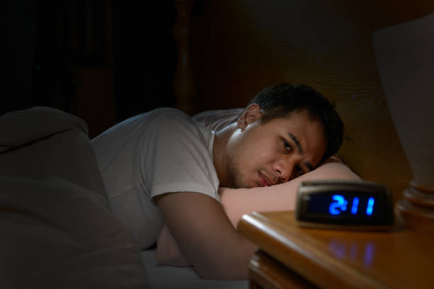 depressed man suffering from insomnia lying in bed - wake imagens e fotografias de stock