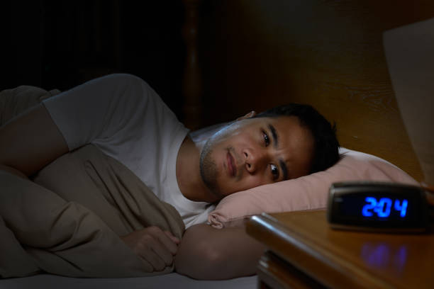 istock Depressed man suffering from insomnia lying in bed 820818594