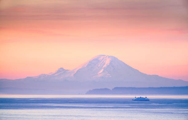 A ferry crossing the Puget Sound at sunrise with Mount Rainier in the background, Washington, USA A ferry crossing the Puget Sound at sunrise with Mount Rainier in the background, Washington, USA mt rainier stock pictures, royalty-free photos & images