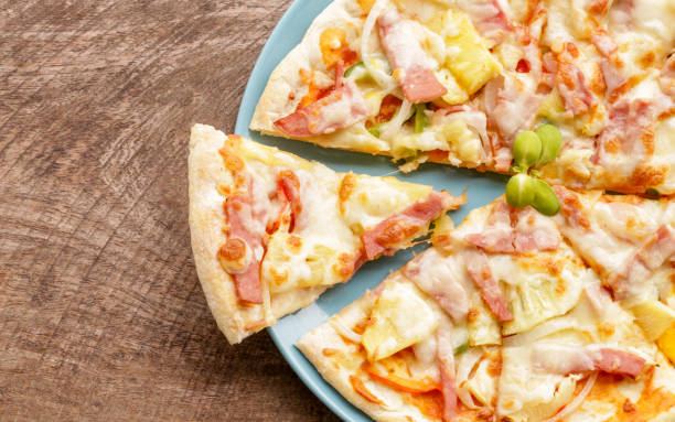 istock Hot pizza slice on wooden table 820821544