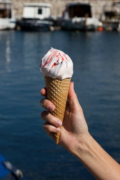istock hand holding fresh ice cream with sea harbor on the background 820831734