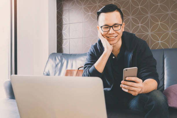 istock Happy asian businessman using smartphone while sitting on sofa at home office background.Concept of young people working mobile devices. 820836128