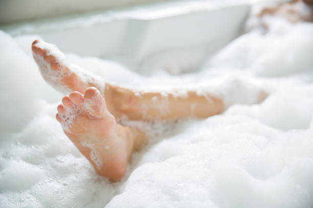 предзнаменование ноги она купалась в ванной со счастьем - human leg women shower water стоковые фото и изображения
