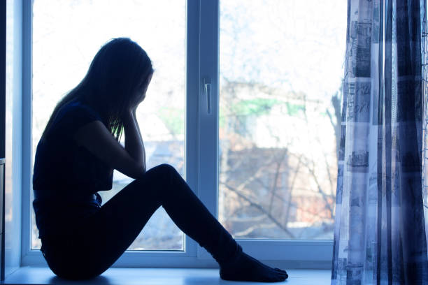 istock Woman sitting on windowsill, crying 820857296